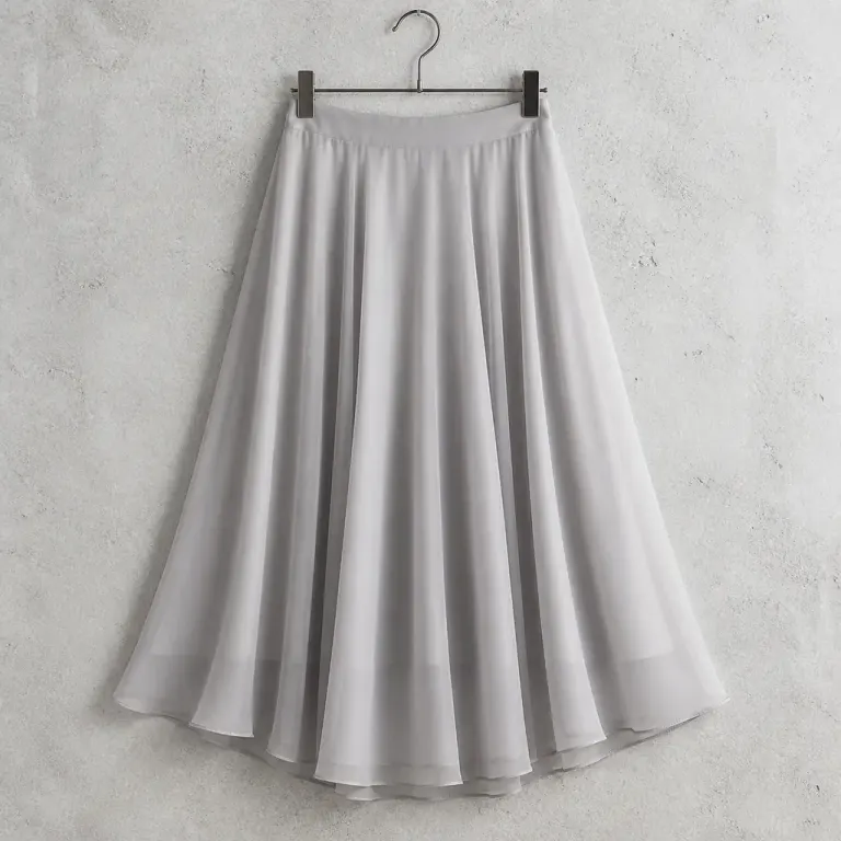 Pale smoke-gray chiffon midi skirt hanging against a concrete wall with translucent backlit folds