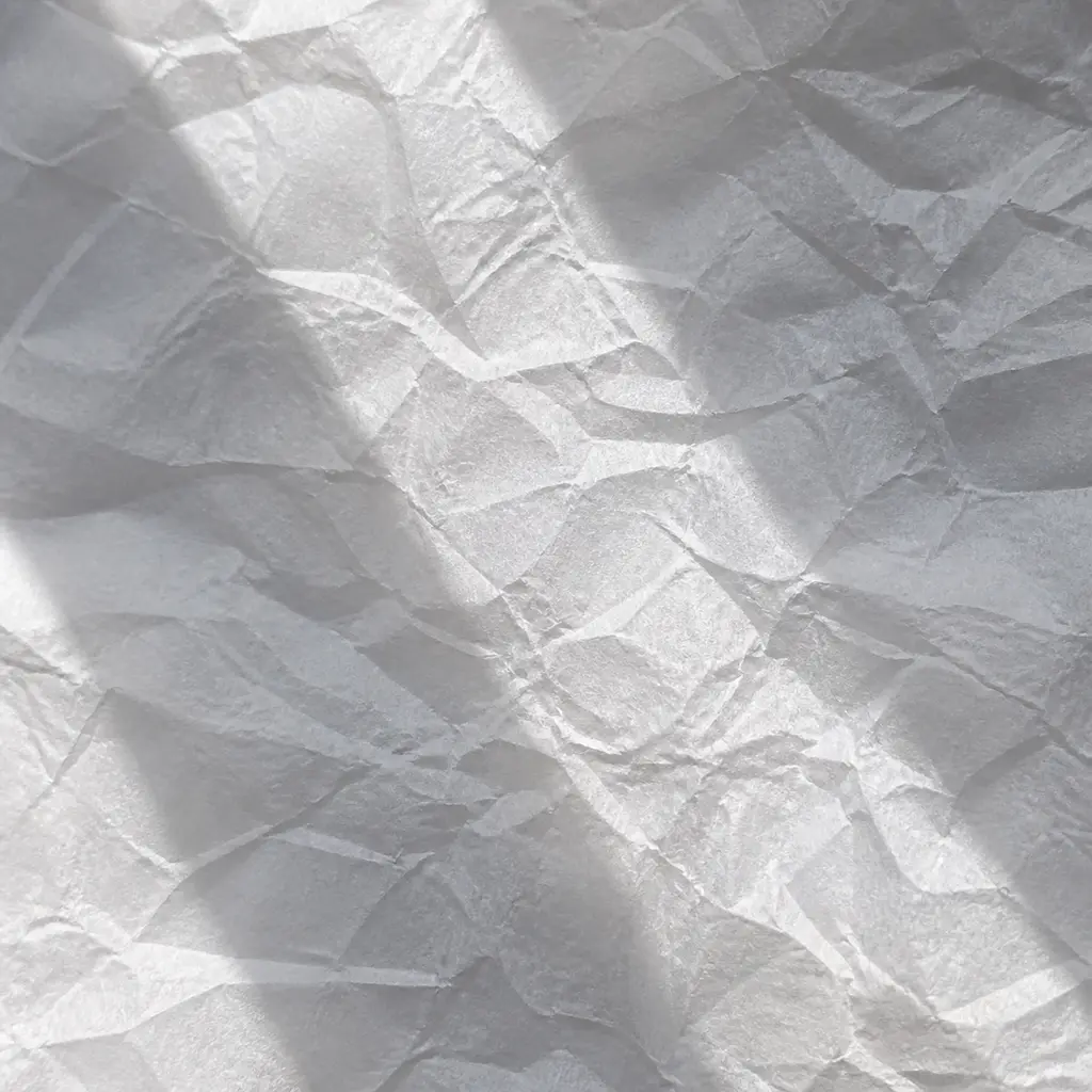 Close texture of crumpled translucent white paper with backlit folds and soft crossing shadows