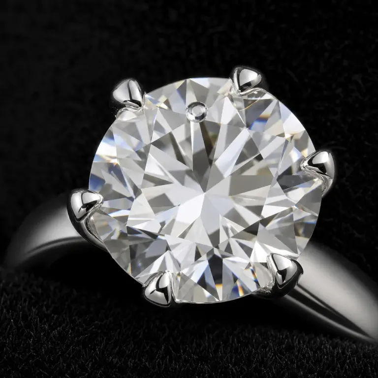 Extreme macro of a diamond solitaire ring with a tiny water droplet on black velvet
