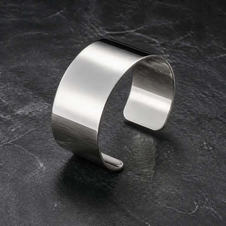 Wide polished silver cuff standing on dark charcoal stone with raking side light