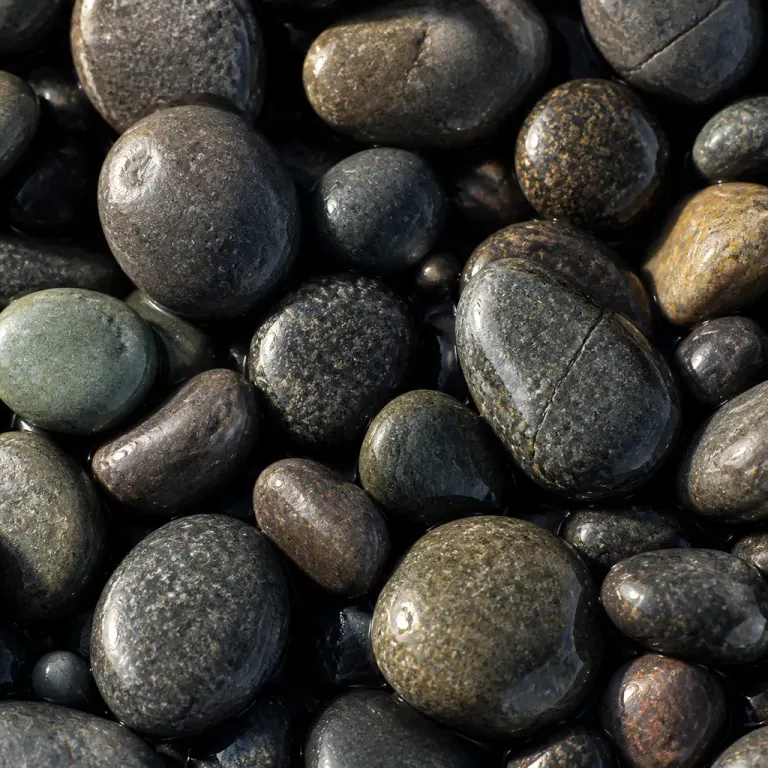 Extreme macro of wet rounded river pebbles reflecting one-sided window light